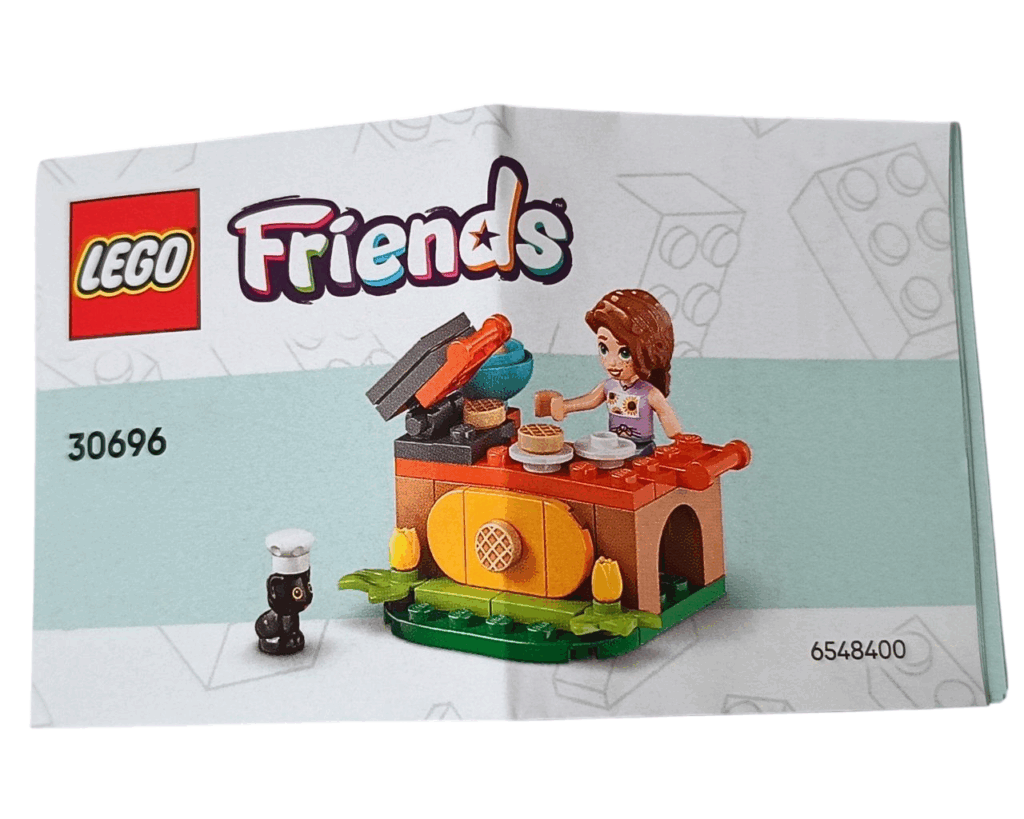 LEGO Friends 30696 オータムのワッフル屋さん 組立説明書表紙。屋台のカウンターでワッフルを焼くオータムと、コック帽をかぶった黒ネコのプルートが描かれている