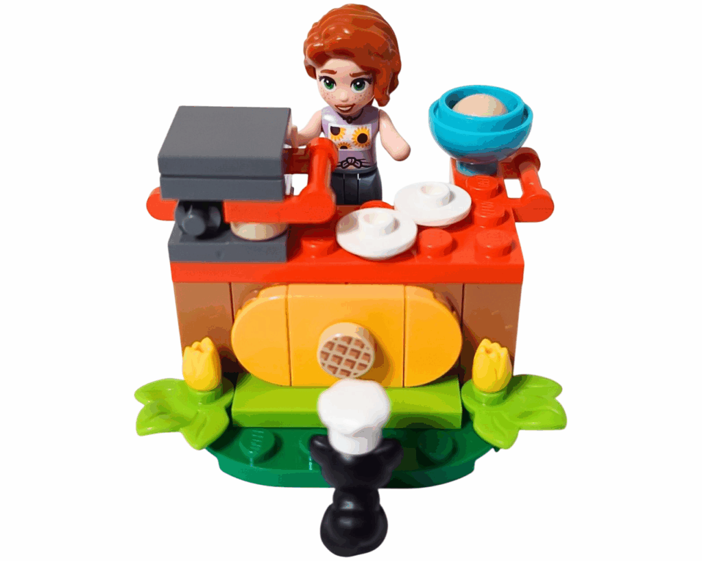 LEGO Friends 30696 オータムのワッフル屋さん 完成シーン。オータムがワッフルメーカーで焼いており、黒ネコのプルートが前で待っている