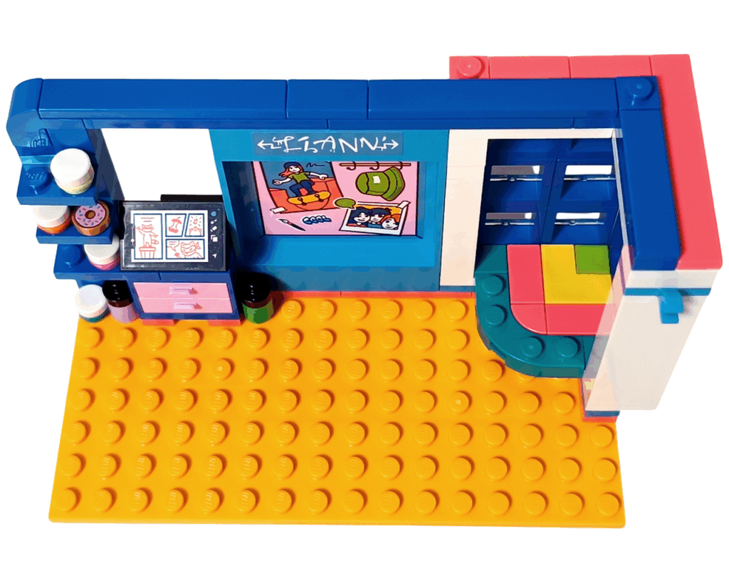 LEGO Friends 41739 リアンの部屋 袋①完成。 青い壁と棚、ピンクの引き出しのイラストデスク、右側にカラフルなコーナーテーブルと大きな窓。全体がオレンジの床の上に配置されている。
