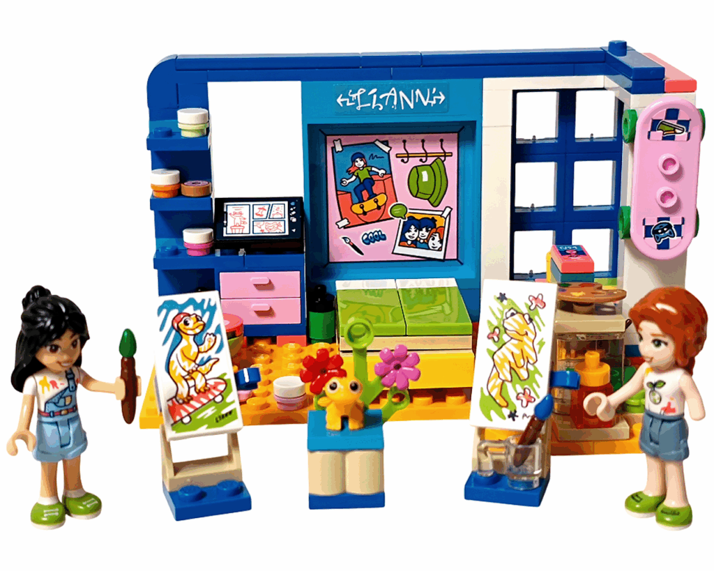 LEGO Friends 41739 リアンの部屋 完成シーン。 リアンとオータムのミニドールが、それぞれ自分の描いたポップコーンの絵をキャンバスに展示し、中央に黄色いヤモリのポップコーンと花の飾りが置かれている。背景には青と白の壁とピンクのスケートボードが飾られている。