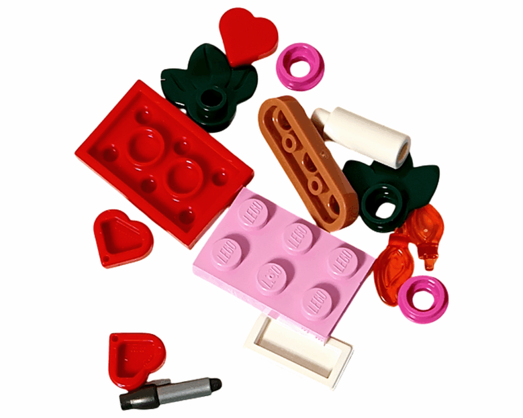 LEGO Friends 42668 9日目のパーツ一覧。ピンクと赤のブロック、キャンドルの炎、葉パーツ、ペンと封筒パーツなど。