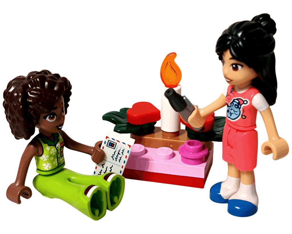 LEGO Friends 42668 手紙を書くアリヤとリアン。アリヤが手紙を持ち、リアンがペンを持って立っている。中央には赤とピンクのキャンドルセットが置かれている。