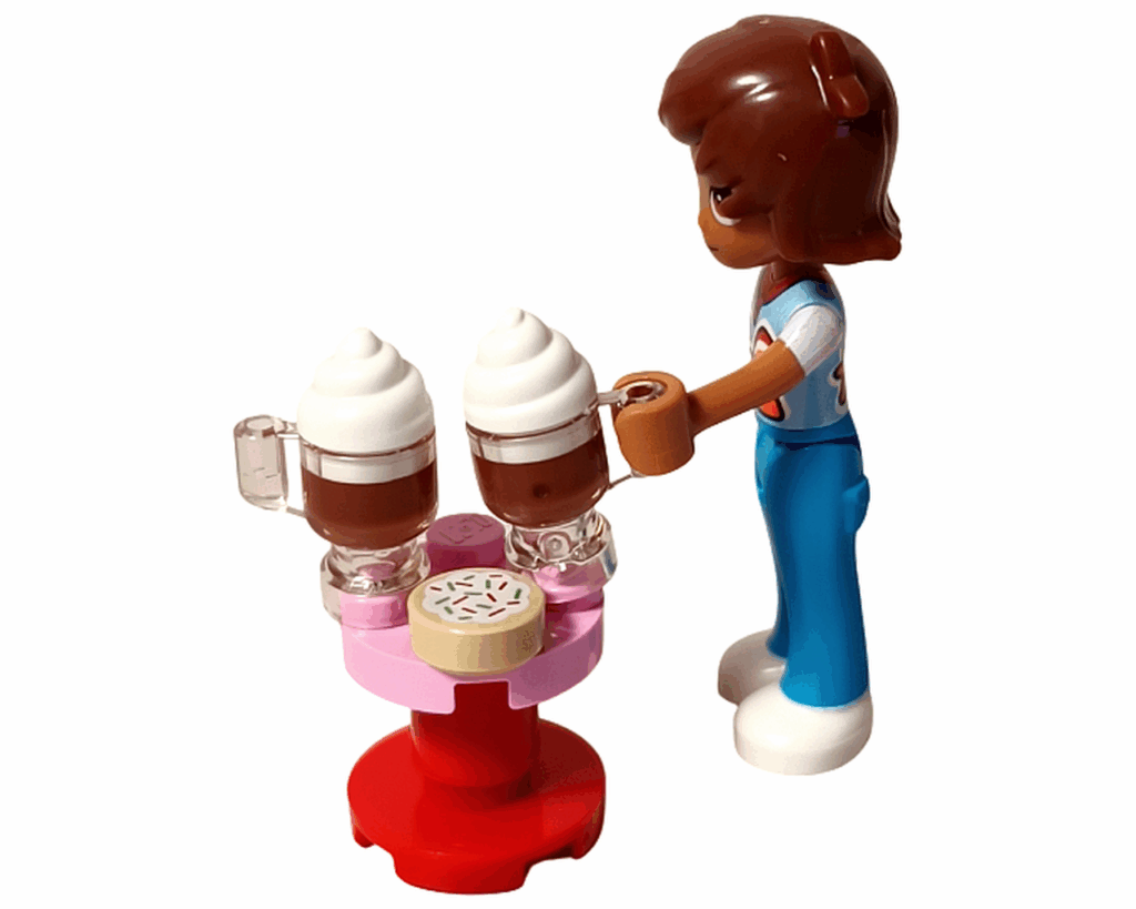 LEGO Friends 42668 レオがホットチョコをテーブルに並べているシーン。ピンクの丸テーブルにホットチョコ2杯とドーナツパーツが置かれている。