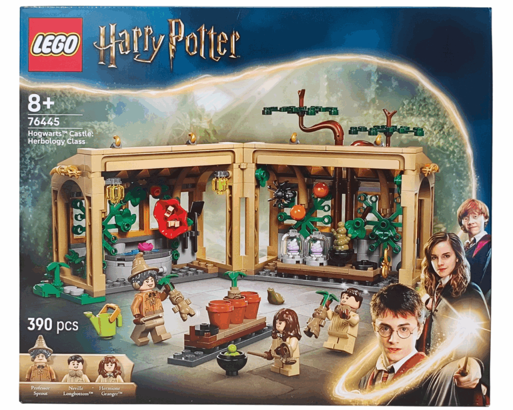 LEGO Harry Potter 76445 ホグワーツ城：薬草学の授業 パッケージ正面。 中央にガラス張りの温室があり、スプラウト先生、ハーマイオニー、ネビル・ロングボトムのミニフィギュアが立っている。 鉢植えのマンドレイクやジョウロ、薬草が並び、背景にはホグワーツ城と夜明けの空が描かれたデザイン。