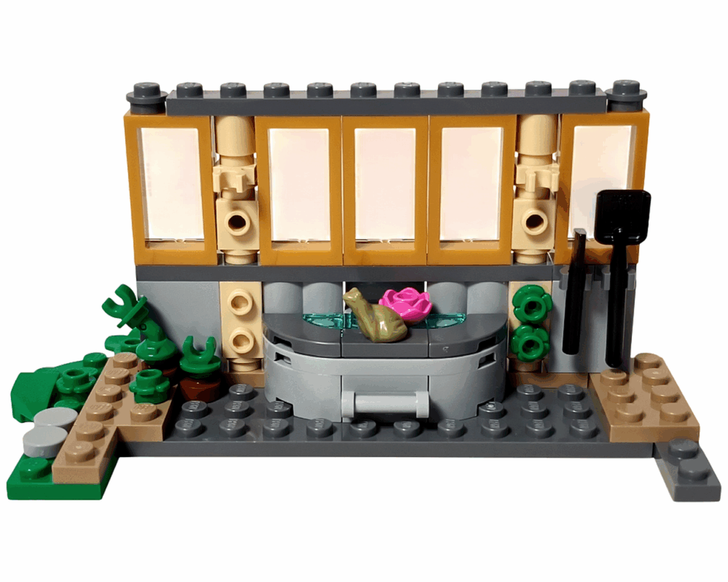 LEGO Harry Potter 76445 ホグワーツ城：薬草学の授業 温室の側面完成。 ベージュのフレームに透明窓を4枚並べ、内部に水場とトレバー、ピンクの花が配置されている。 右側の壁には黒いスコップとツールパーツがかけられている。