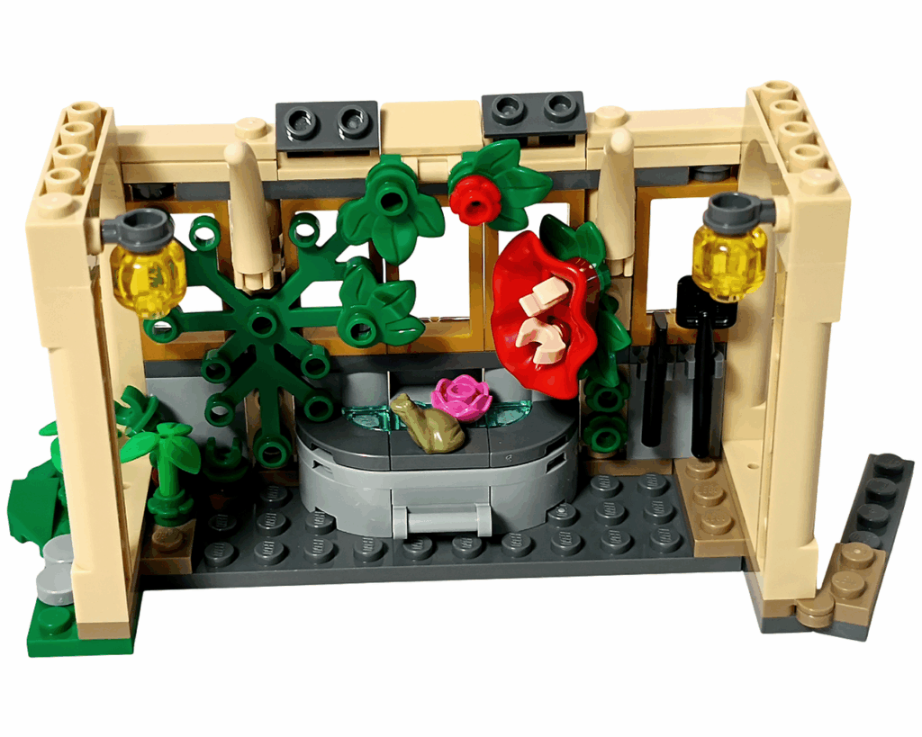 LEGO Harry Potter 76445 ホグワーツ城：薬草学の授業 2袋目完成。 ベージュのアーチ壁とガラス窓で囲まれた温室内に、 水場・トレバー・赤い花・緑のツタが配置され、上部に2つの金色ランプが取りつけられている。