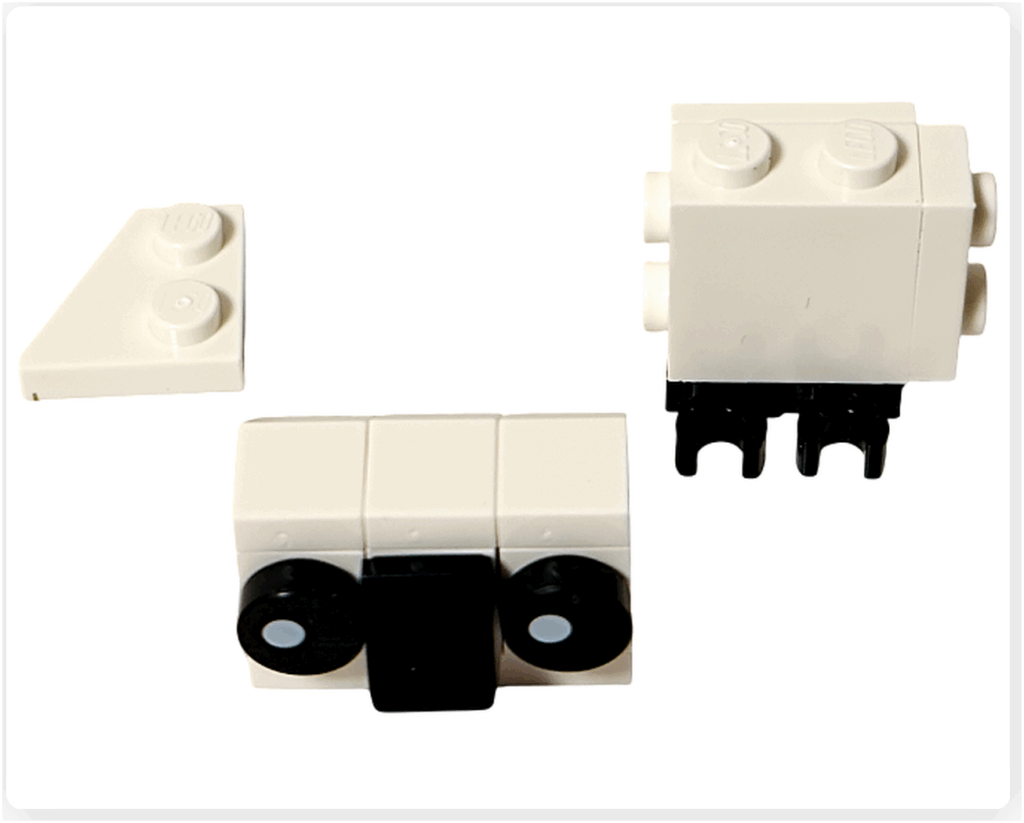 LEGO Harry Potter 76456「ハリー・ポッター アドベントカレンダー2025」2日目のヘドウィグ組立途中。 白いブロックが胴体を形づくり、黒い丸パーツで目とくちばしが再現されている。 下部に黒い足パーツが取りつけられた状態。