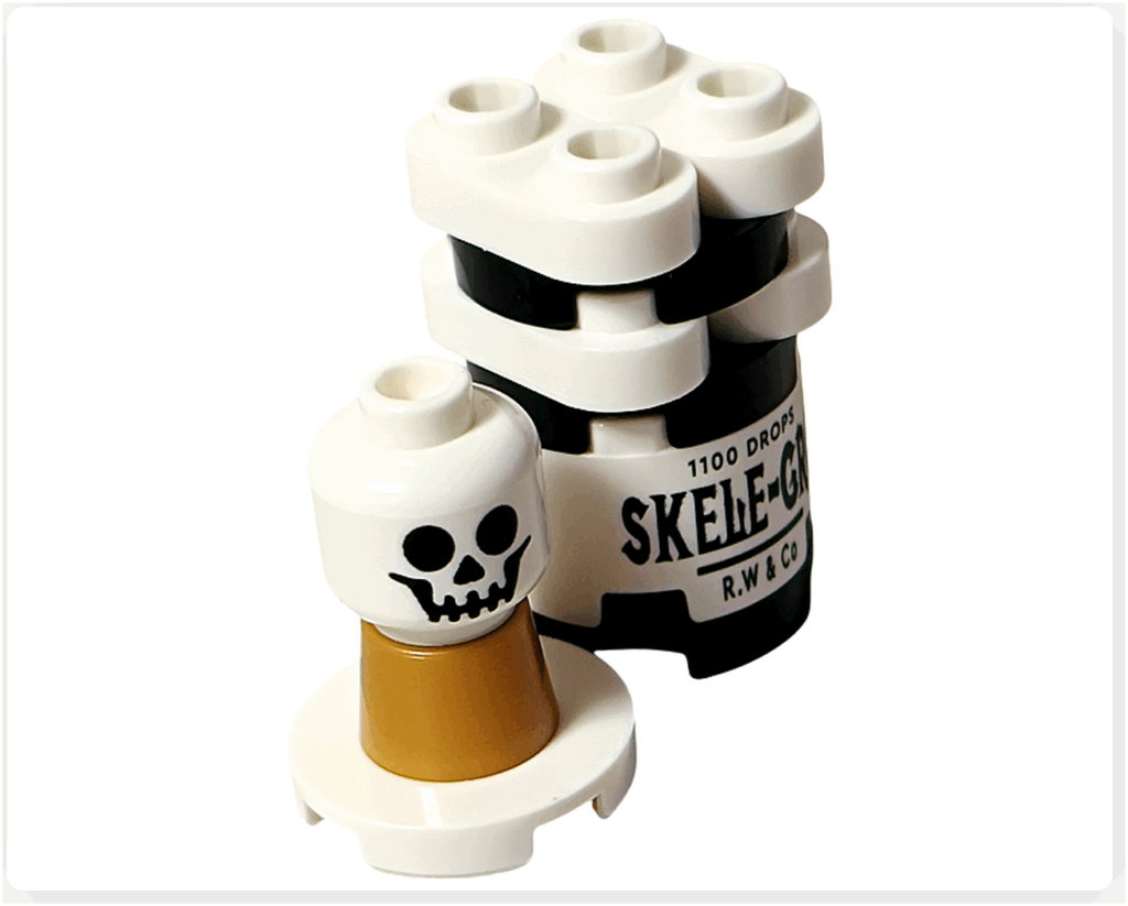 LEGO Harry Potter 76456 アドベントカレンダー2025 18日目のスケレ・グロ組立途中。 白と黒のブロックでボトル部分が組み上がり、手前に金色のフタと骸骨プリントのパーツが置かれている。
