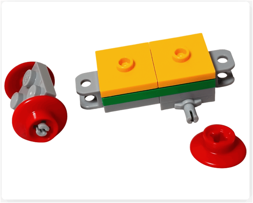 LEGO Friends アドベントカレンダー2023 22日目の組立途中。黄色と緑のブロックで荷台部分を作り、グレーの連結パーツが左右に伸びている状態。赤い車輪パーツはまだ取り付け前。