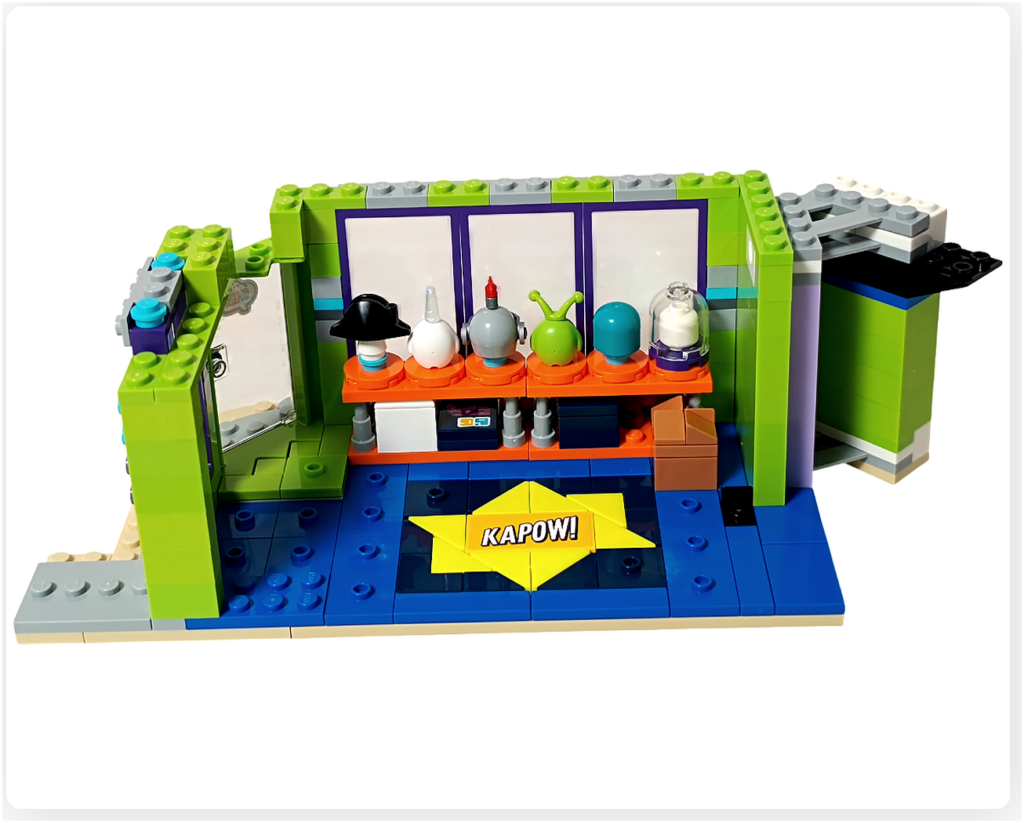 レゴ フレンズ 42674 コミックショップとゲームセンター。1階ゲームセンター店内に配置されたメダルストックの様子。ディスプレイ棚の下に小さな茶色のボックスが置かれている。