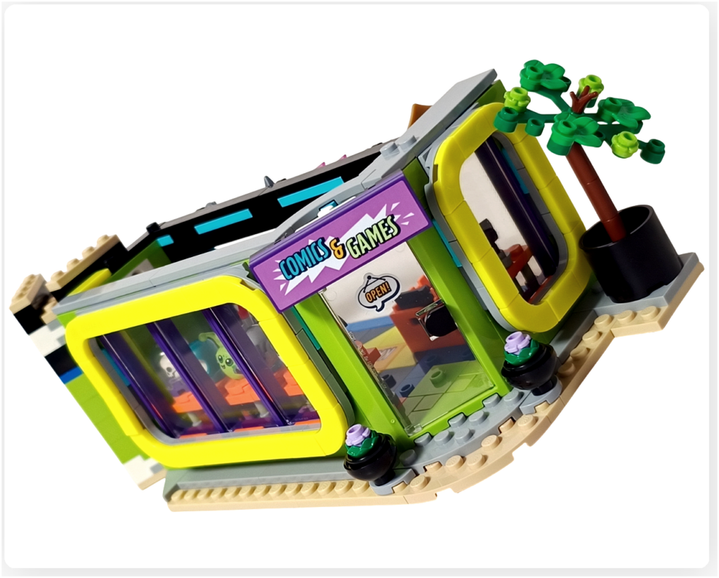 レゴ フレンズ 42674 組立レビューの写真。コミックショップとゲームセンターの1階外観で、入口上に「COMICS & GAMES」のショップ看板が取り付けられ、植木やウインドウ装飾を含む外観が完成している様子。