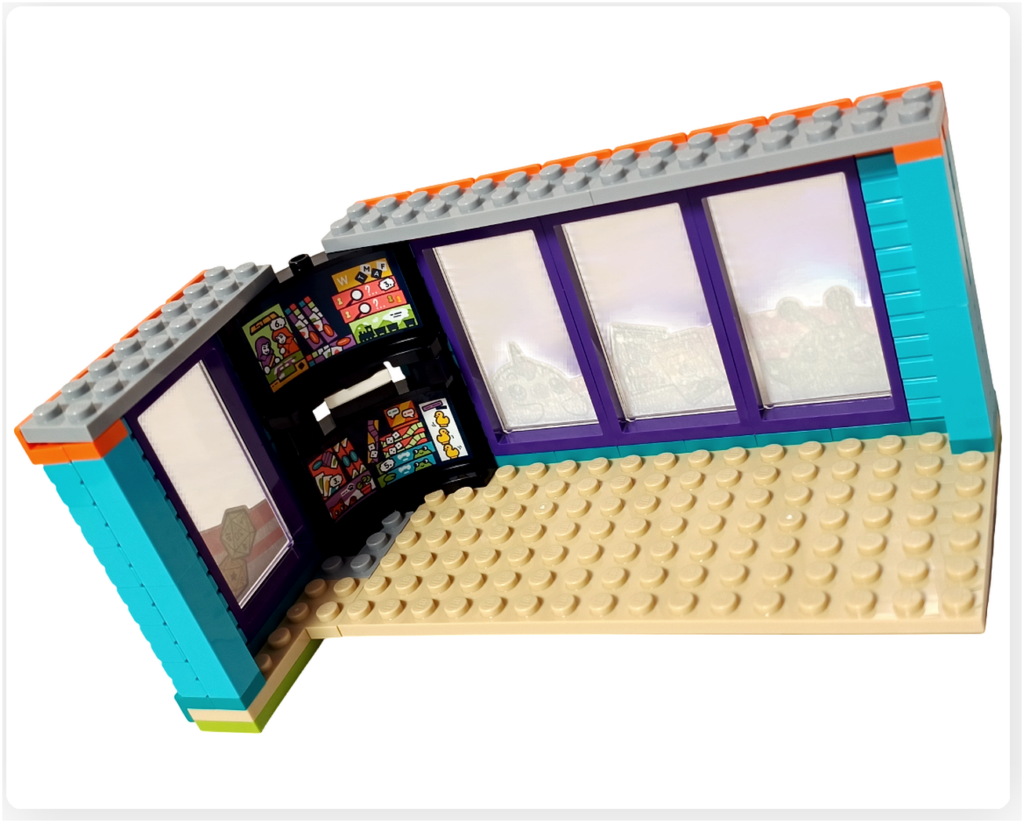 レゴ フレンズ 42674 コミックショップとゲームセンターの2階ゲームセンター内装。コーナー部分にゲームソフト棚が配置され、壁面スクリーンや床構造とあわせて上階の遊び空間がわかる様子。