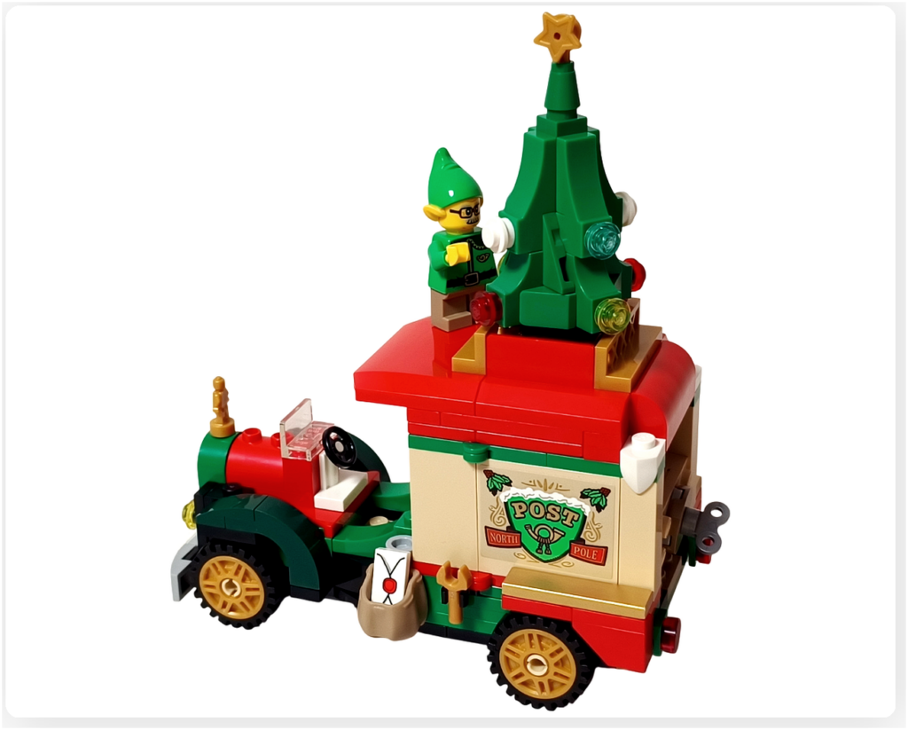 レゴ 40746 シーズナル クリスマスプレゼント配達トラックの完成シーン。屋根の上でエルフがミニクリスマスツリーの飾りを点検している様子を写した写真で、赤い屋根や金色ホイールなど車体外観の特徴も分かる構図です。
