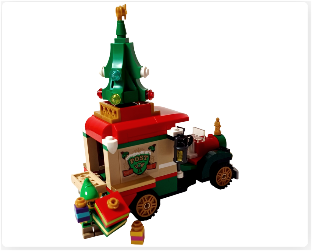レゴ 40746 シーズナル クリスマスプレゼント配達トラックの完成シーン。荷台のふたを開け、エルフのミニフィギュアが複数のプレゼントを抱えて運び出している様子。赤い屋根の車体や側面のPOSTロゴ、屋根上のツリー装飾が確認できる写真です。
