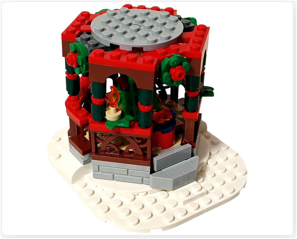 レゴ 40778 雪のあずまや(Winter Gazebo)モデルに天井パーツを取り付けた様子。赤と緑の装飾柱に囲まれた屋根の上に、丸いグレーの天井プレートが固定されている。