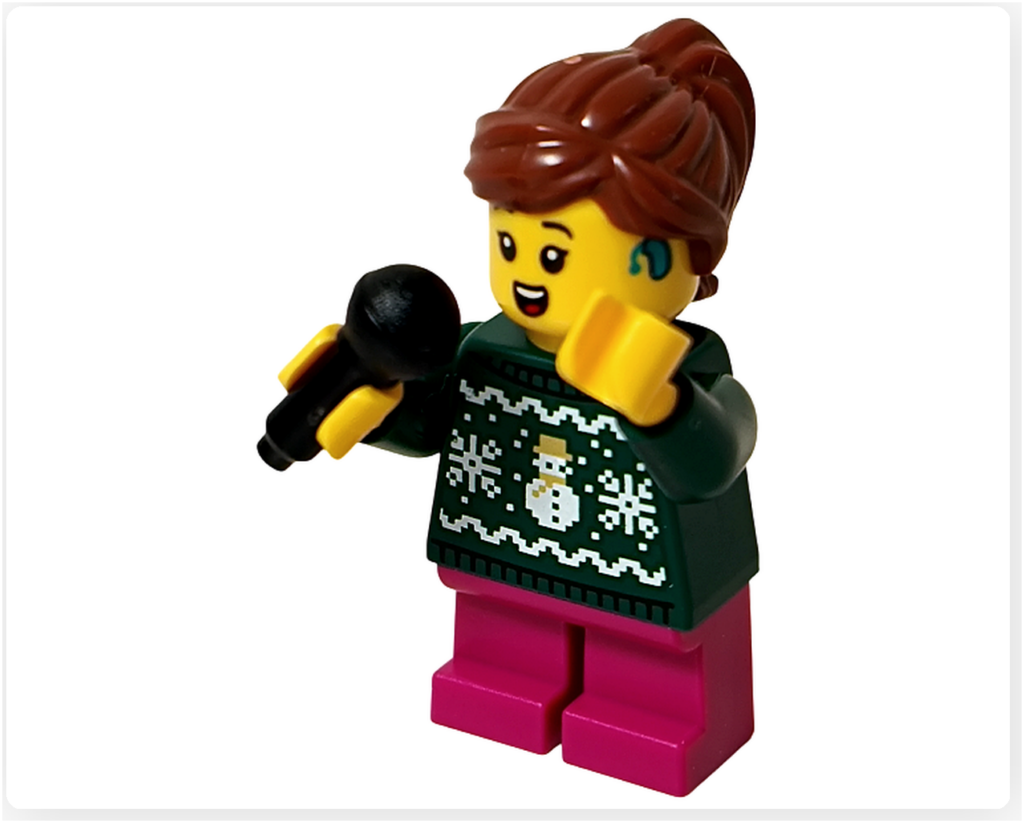 レゴ 40778 雪のあずまや（Winter Gazebo）に含まれるキャロル合唱団の歌い手ミニフィグの歌唱ポーズ。マイクを口元に構え、片手を添えた仕草と、雪だるま柄のセーター、ポニーテールの髪型が確認できる。