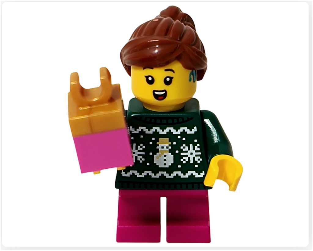 レゴ 40778 雪のあずまや（Winter Gazebo）に含まれるキャロル合唱団の歌い手ミニフィグのプレゼント持ちポーズ。ピンク色のギフトボックスを手に持ち、雪だるま柄の濃いグリーンのセーターとピンクのパンツ、ポニーテールの髪型とイヤーピース風の装飾が確認できる。