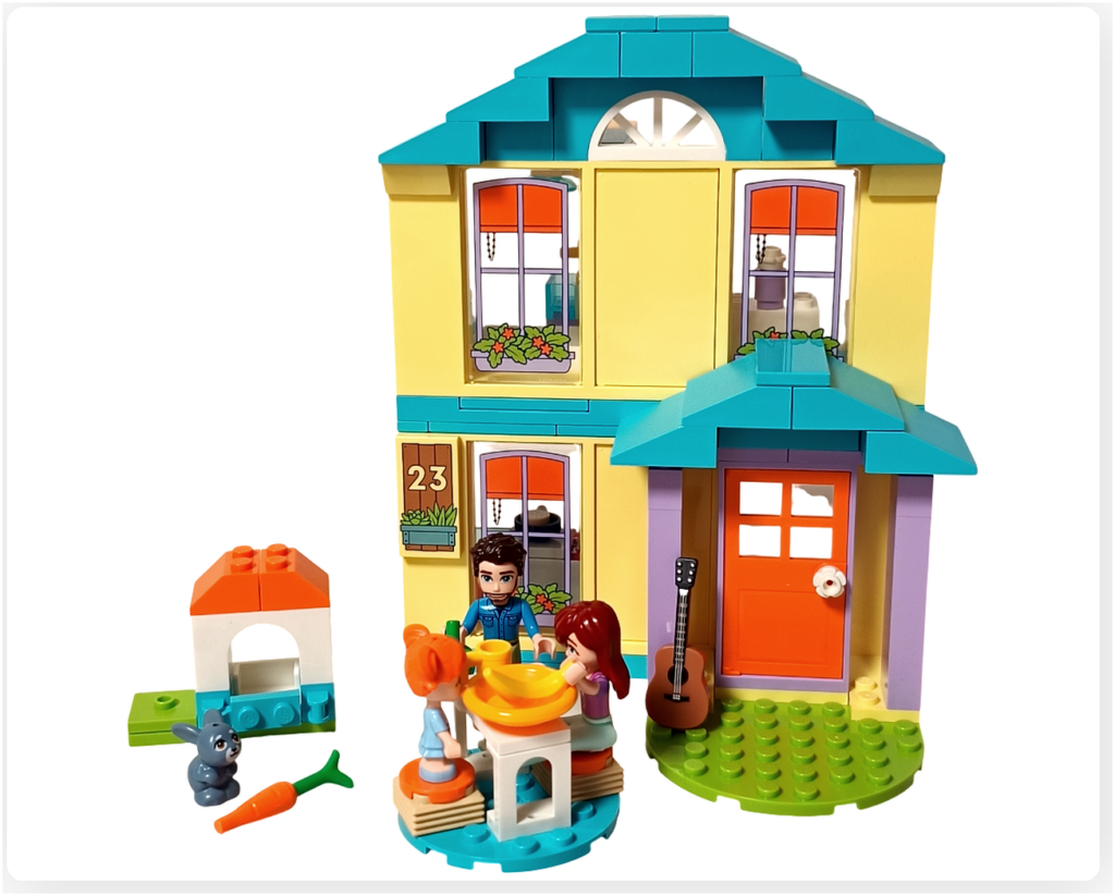 レゴ フレンズ 41724 「ペイズリーのおうち」の完成シーン。庭のテーブルでジョナサン、エラ、ペイズリーが昼食をとり、そばにメロディと玄関前に置かれたギターがある様子。